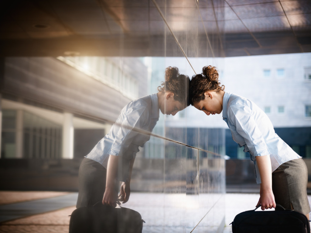 sad businesswoman mid adult italian woman banging her head against a wall outside office building. Horizontal shape, copy space